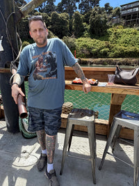 Load image into Gallery viewer, Customer wearing the When Men Were Men bear wrestling tee dockside at a harbor