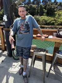 Load image into Gallery viewer, Bear wrestling graphic tee worn by a customer on a fishing dock in the sun